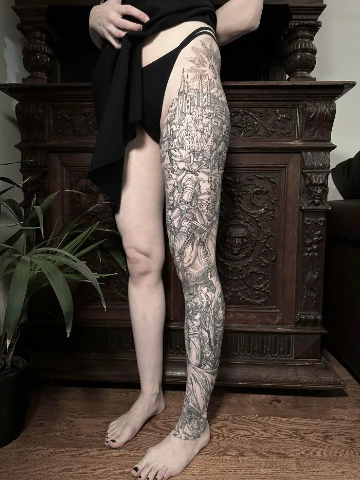 A detailed black and grey leg sleeve tattoo featuring a complex scene, a stunning tattoo that someone is happy to wear forever.