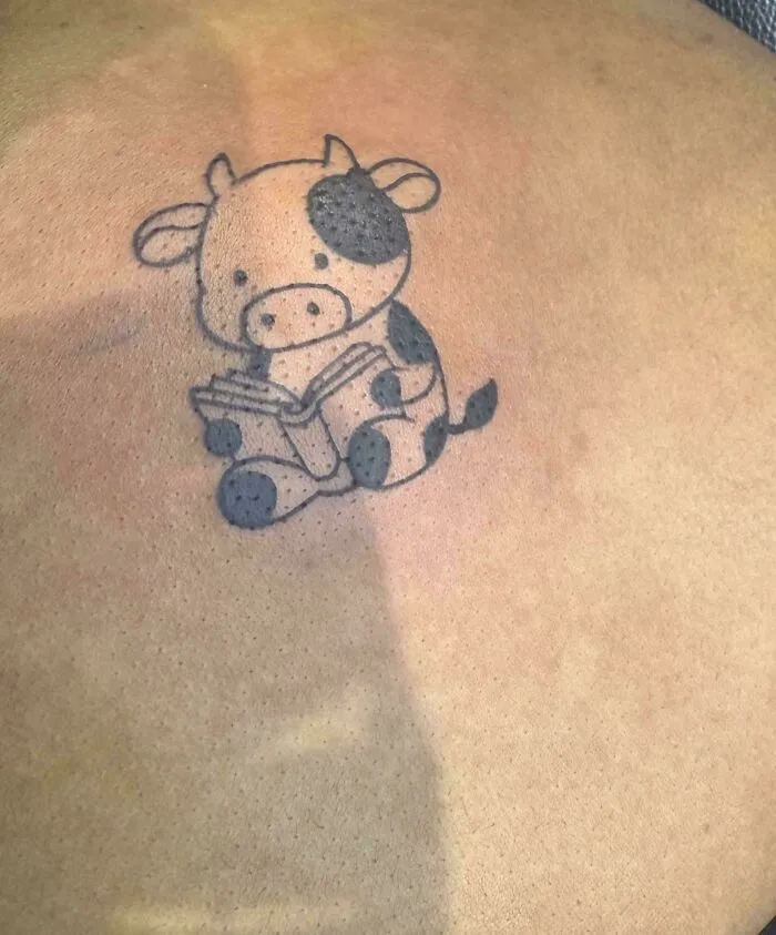 A small, cute calf reading a book, a happy tattoo that people wear forever.