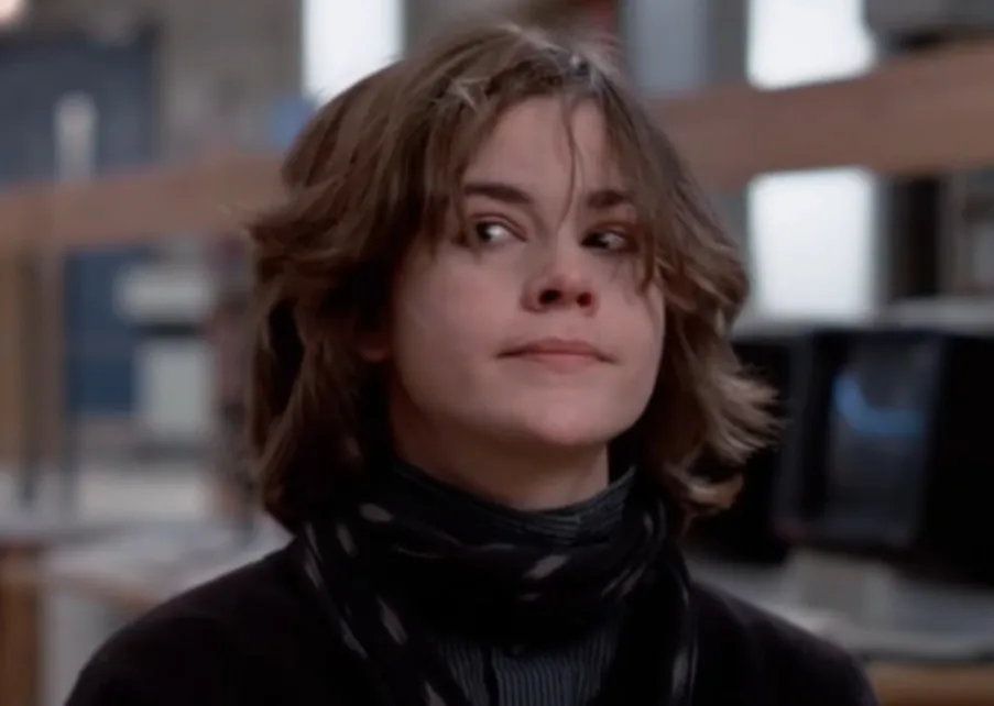 Allison from The Breakfast Club looking to the side with messy hair and a serious expression in school setting.