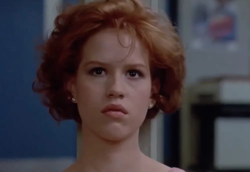 Claire from The Breakfast Club with a serious face, showing emotion in a school setting.