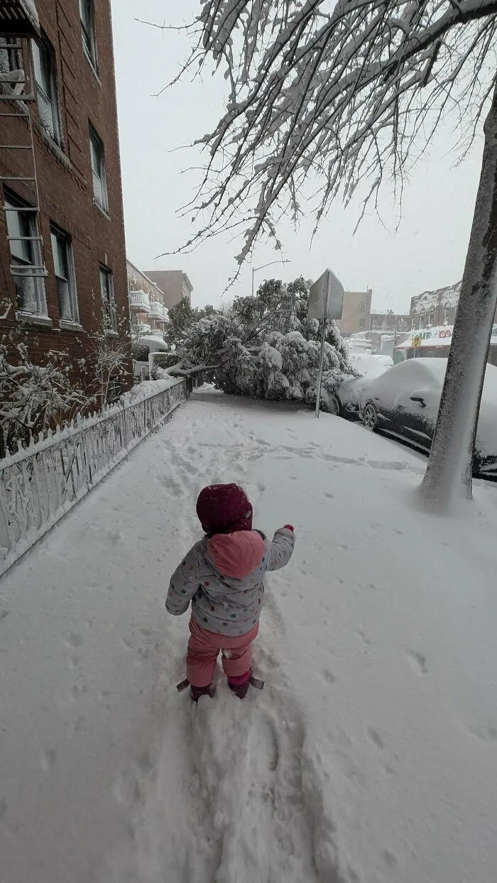 A small child in a snowsuit walks through deep snow, representing the funny, goofy, and great dad moments.