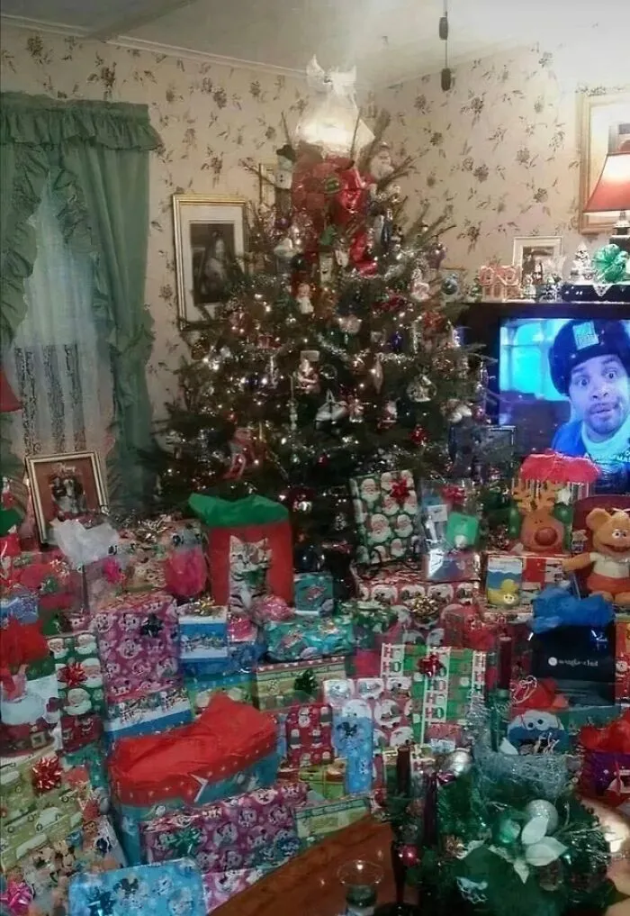 Christmas tree surrounded by 90s-themed wrapped gifts and a TV showing a 90s TV show scene in a cozy living room.