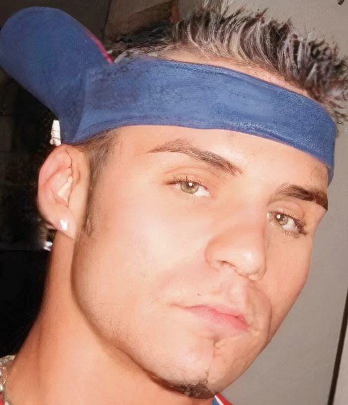 Close-up of a young man wearing a blue visor, styled with ’90s fashion, capturing the essence of childhood memories.