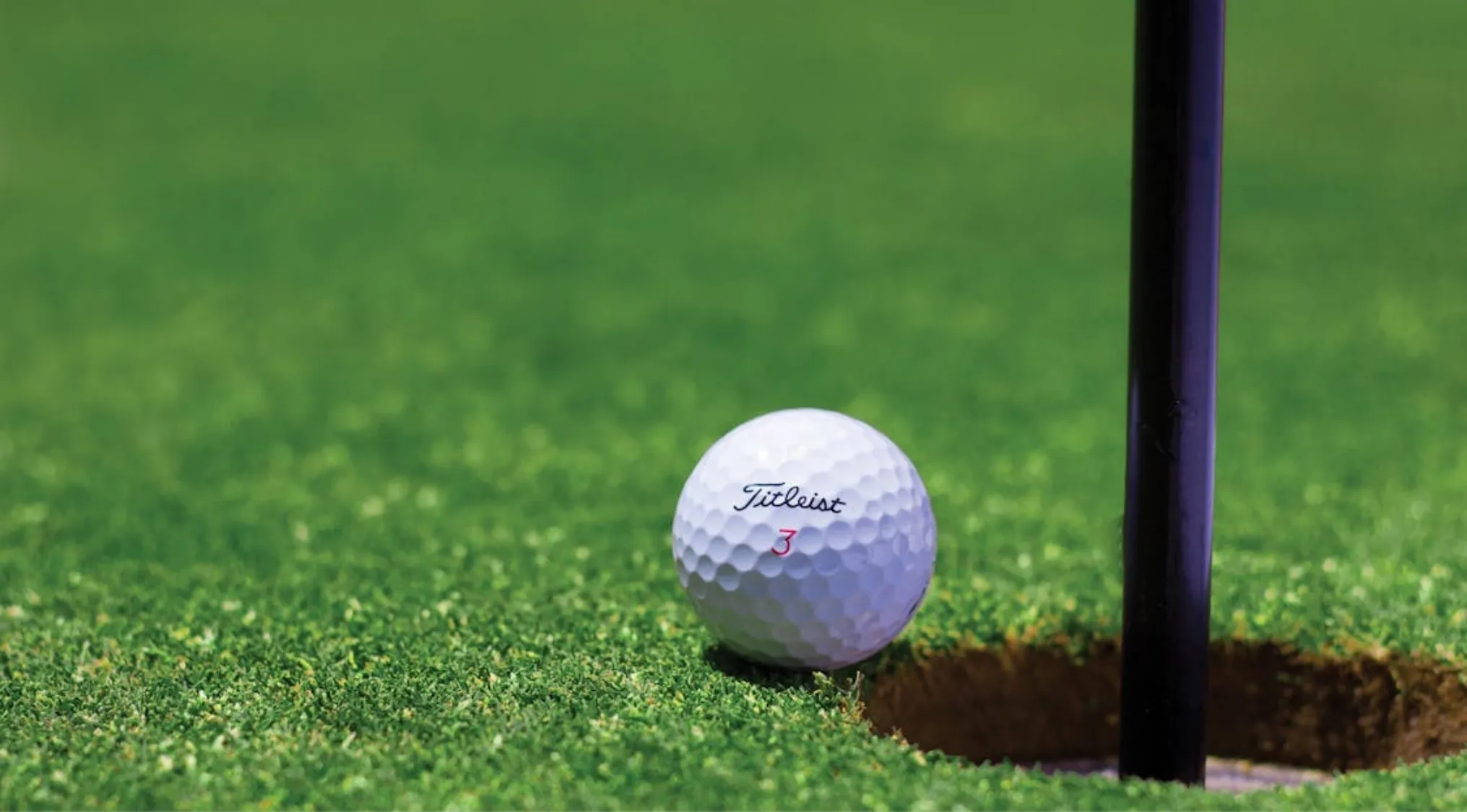 Close-up of a golf ball near the hole on a green, illustrating golf popularity in the 1970s with stars like Björn Borg.