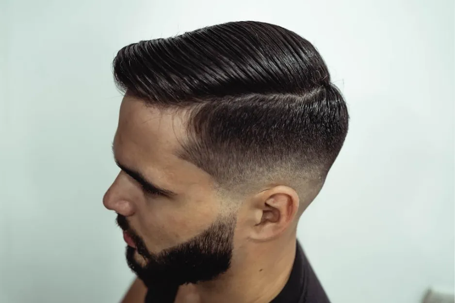 Man with a 1970s style undercut hairstyle, neatly combed on top and faded on the sides with a trimmed beard.