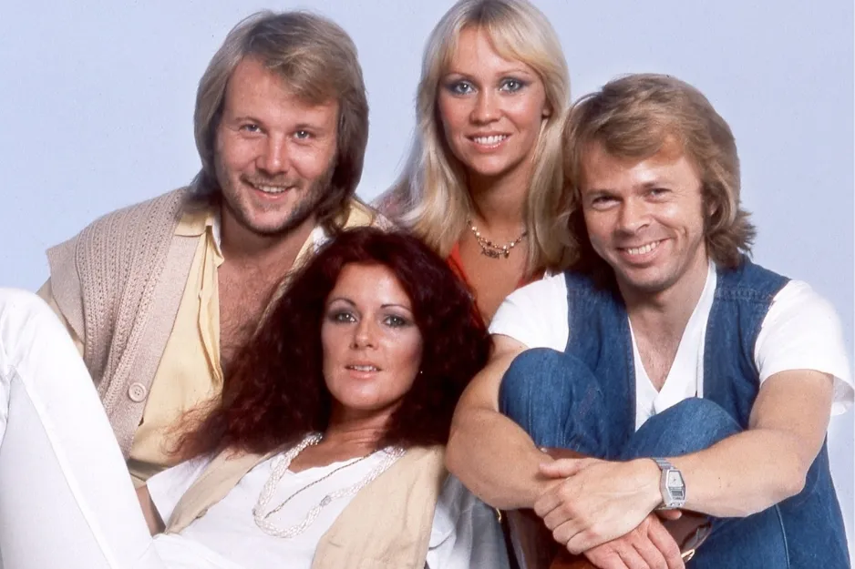 The Swedish pop group ABBA posing together in casual 1970s attire with smiling expressions.