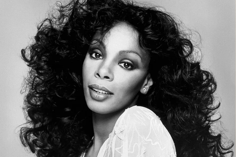 Donna Summer portrait with voluminous curly hair, wearing a light-colored top, representing the queen of disco.