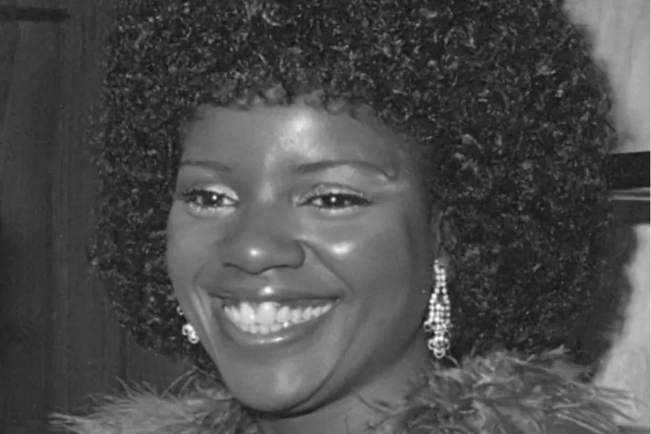 Gloria Gaynor smiling with earrings and curly hair, known as Queen of Disco and hit singer of Hot Stuff.