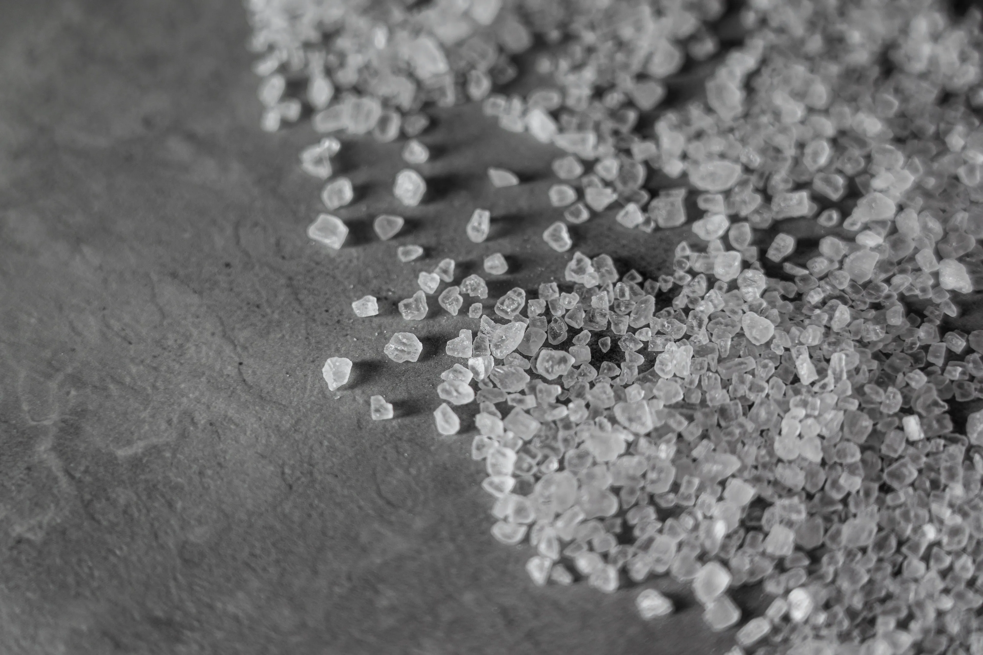 Close-up of salt crystals on a surface illustrating the salt formed when hydrochloric acid reacts with sodium hydroxide.