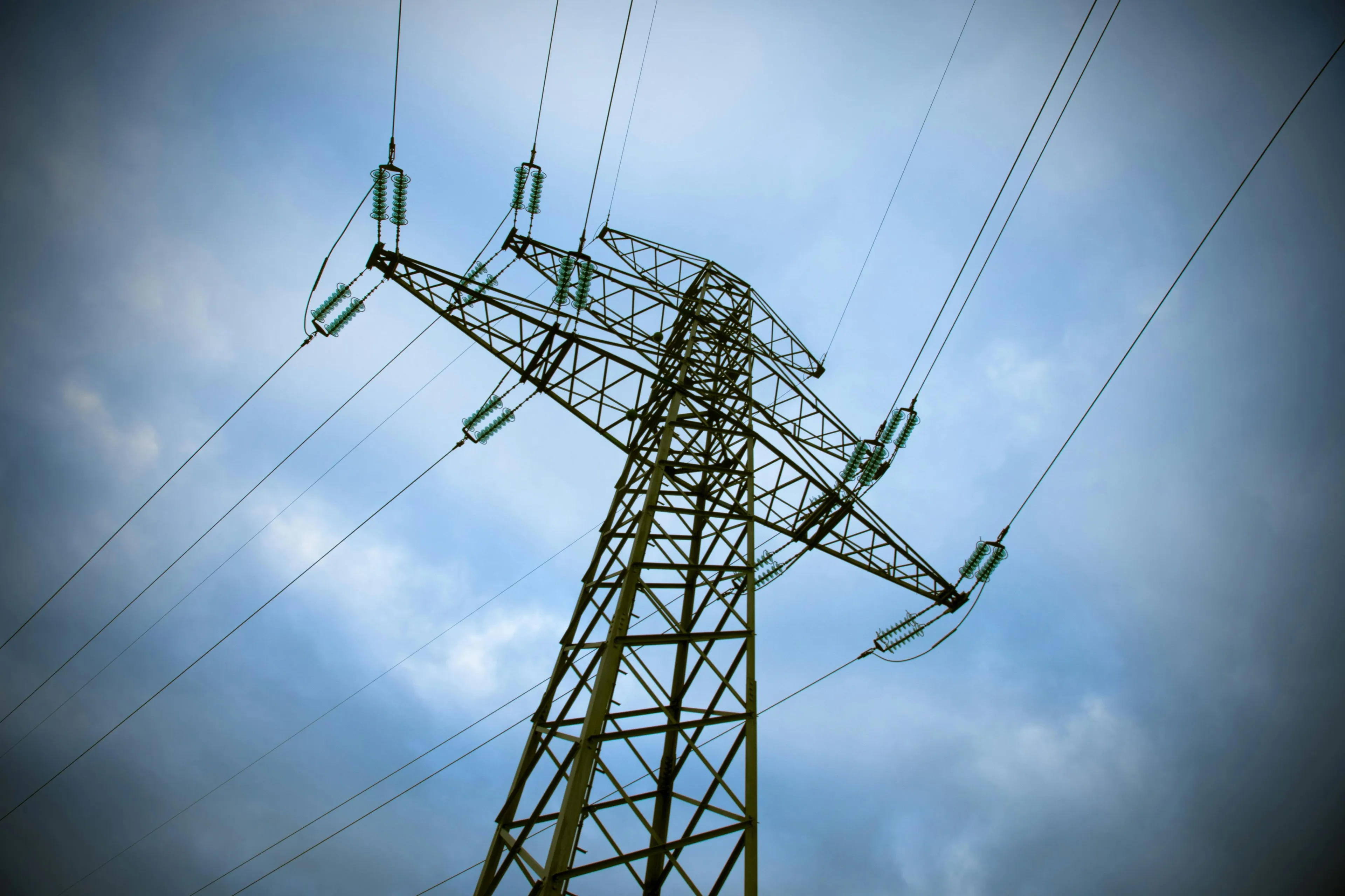 High voltage power lines on a metal tower against a cloudy sky illustrating GCSE Combined Science quiz unit of current concept.