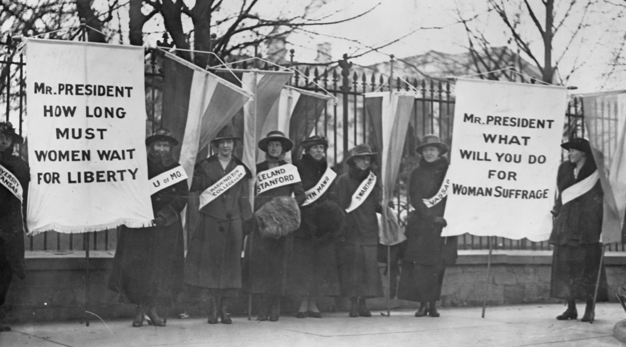 Women suffrage protesters holding banners demanding voting rights and liberty before the 19th Amendment ratification.