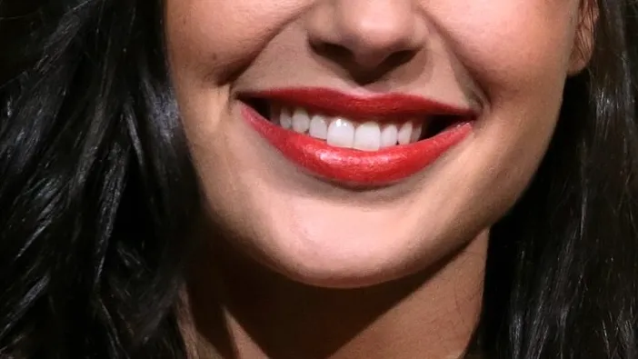 Close-up of a smiling celebrity's mouth with red lipstick, part of a guess the celebrity challenge from their mouth.