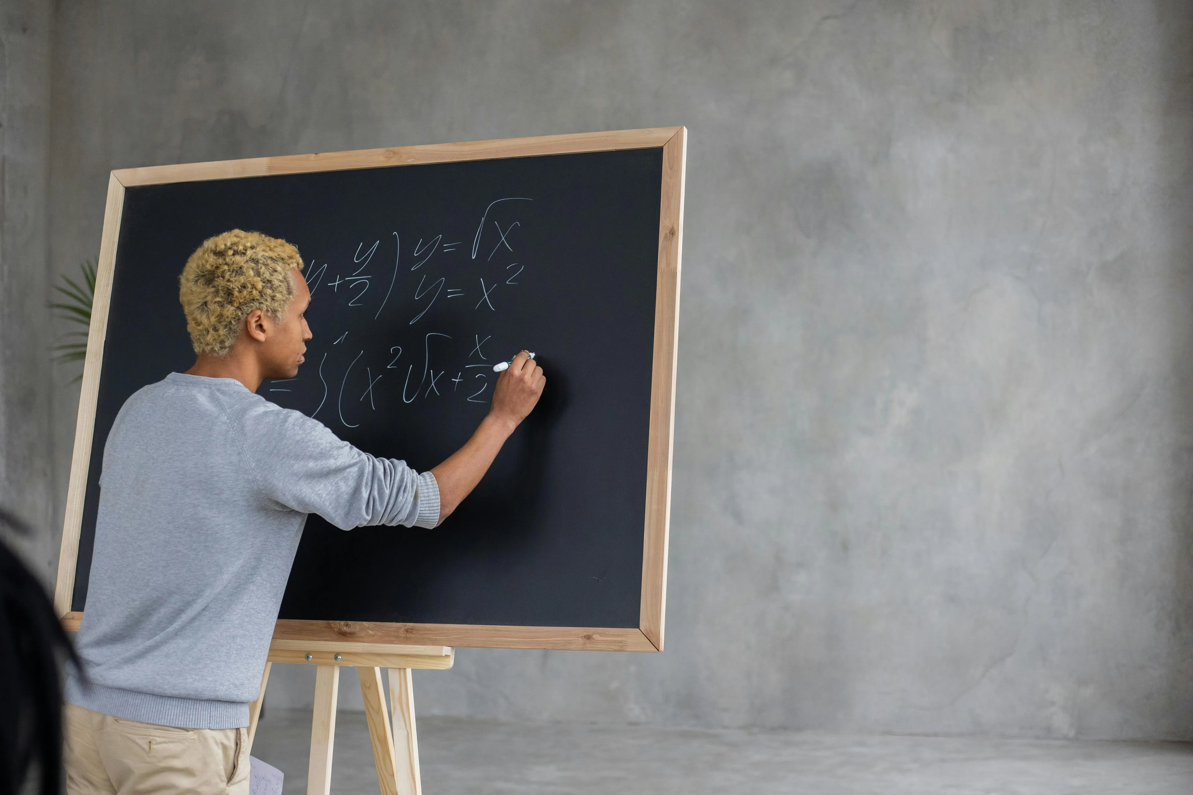 Person solving math equations on a blackboard, illustrating a difficult general knowledge quiz for high IQs.