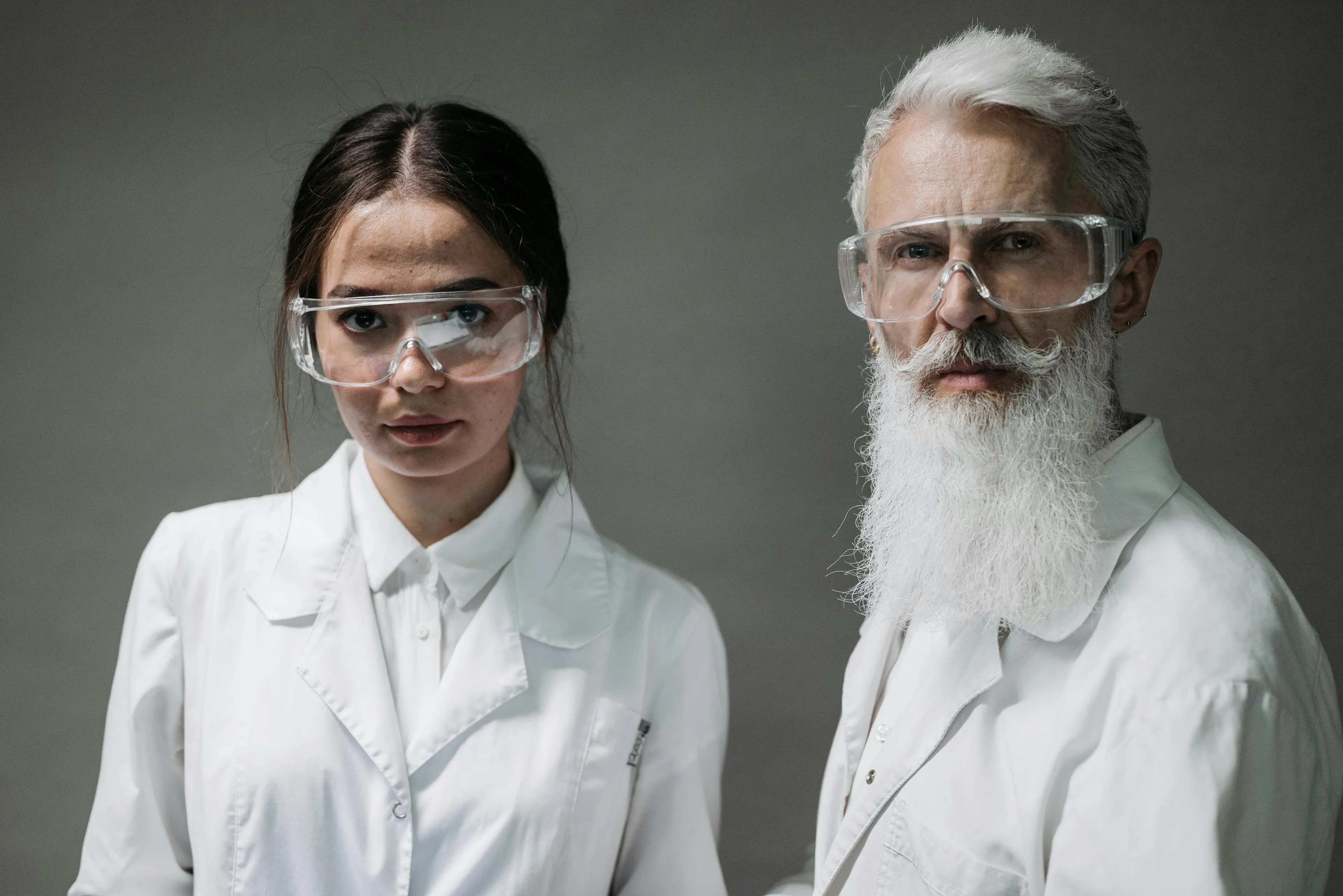 Two scientists wearing white lab coats and safety goggles representing the uncertainty principle concept for high IQ quiz.