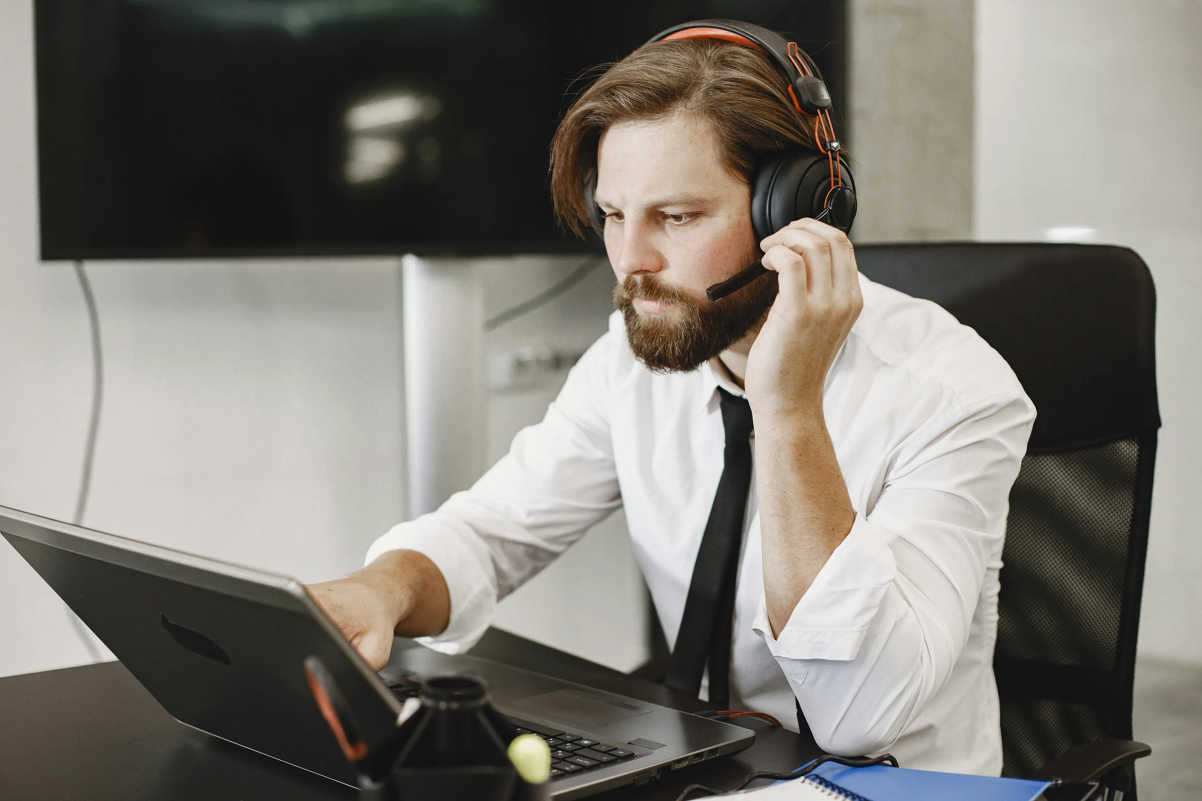 Man with headset working on laptop, focused on economics quiz about Gini coefficient measuring income inequality.