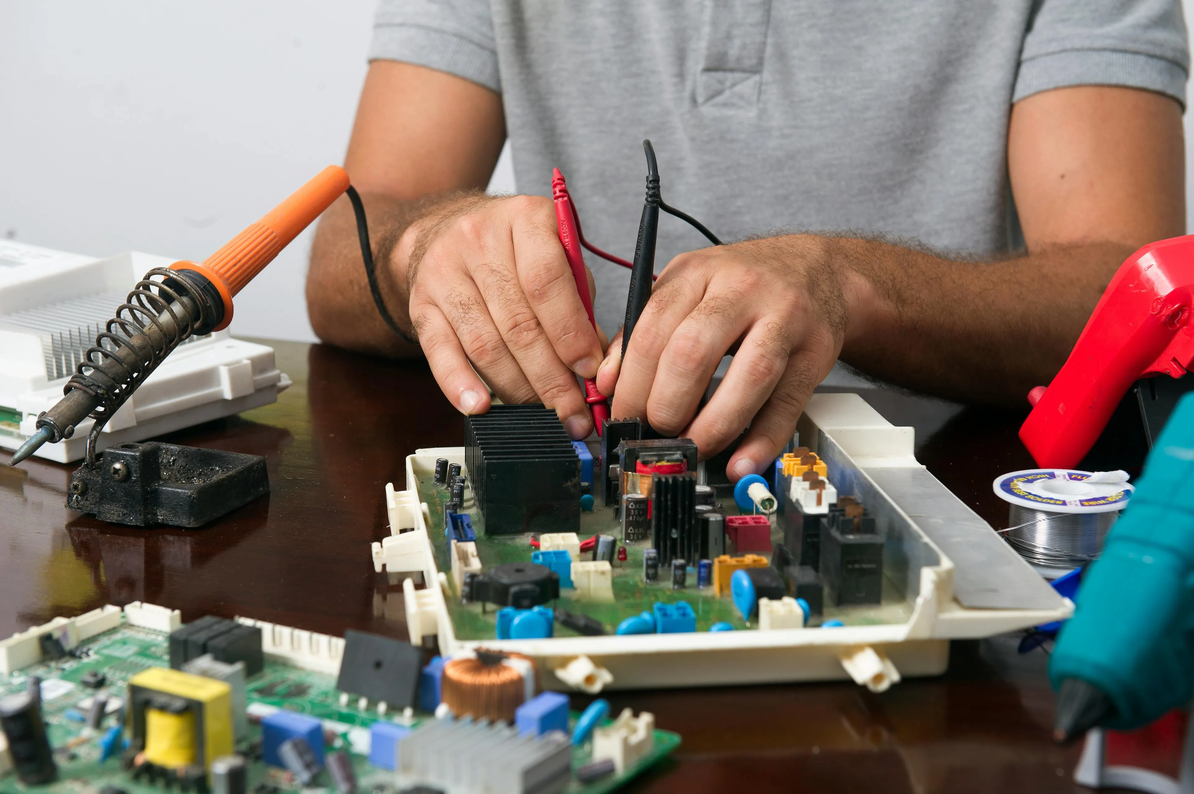 Technician testing electrical conductivity of metal components on a circuit board using probes at room temperature.