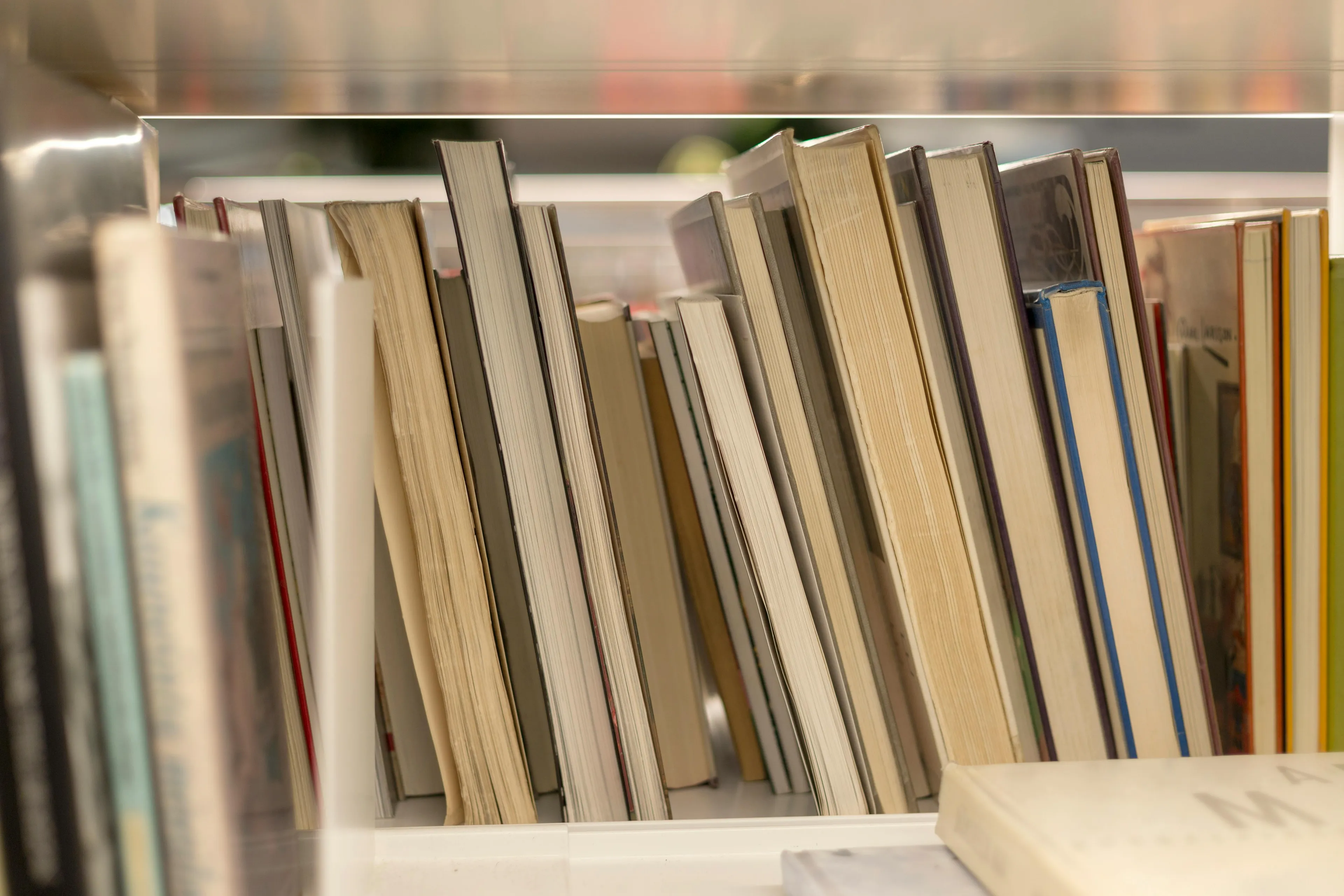 Books lined up on a shelf in a library, related to a difficult general knowledge quiz about Enlightenment thinkers.