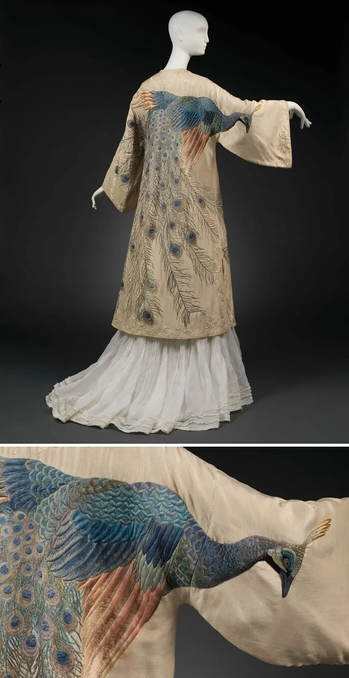 Historical garment featuring detailed embroidered peacock design on silk fabric with long flowing skirt and wide sleeves.
