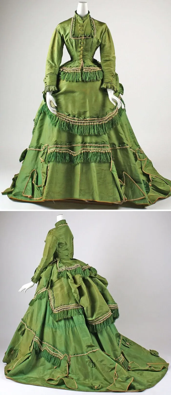 Green historical garment with intricate fringe details, a fitted bodice, and a voluminous skirt showcased on a mannequin.
