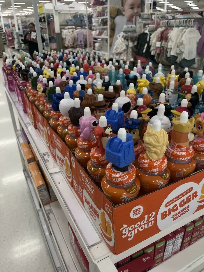 Rows of Good2Grow drinks with character tops in a store aisle, a prime example of consumerism and 400% price difference.