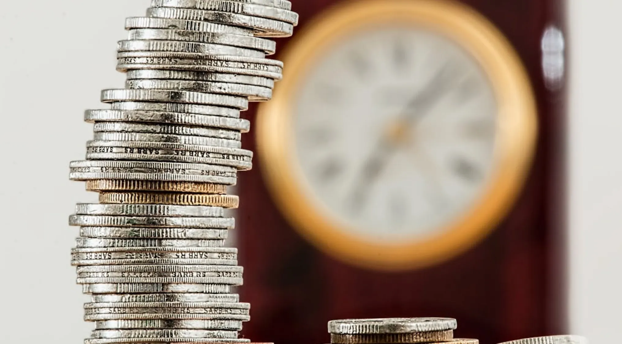 Stack of coins symbolizing money growth over time with a blurred clock in the background representing time factor increase