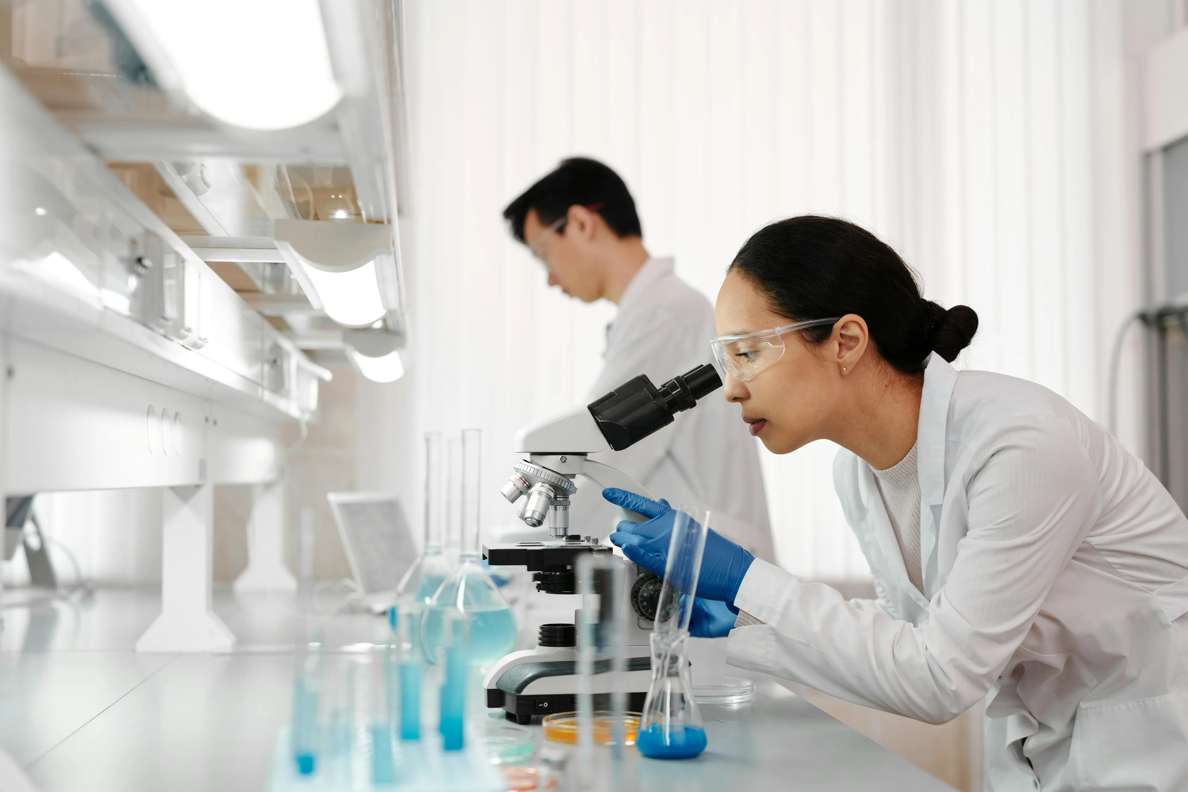 Scientist examining samples under microscope in a lab, demonstrating differences in scientific theory versus hypothesis.