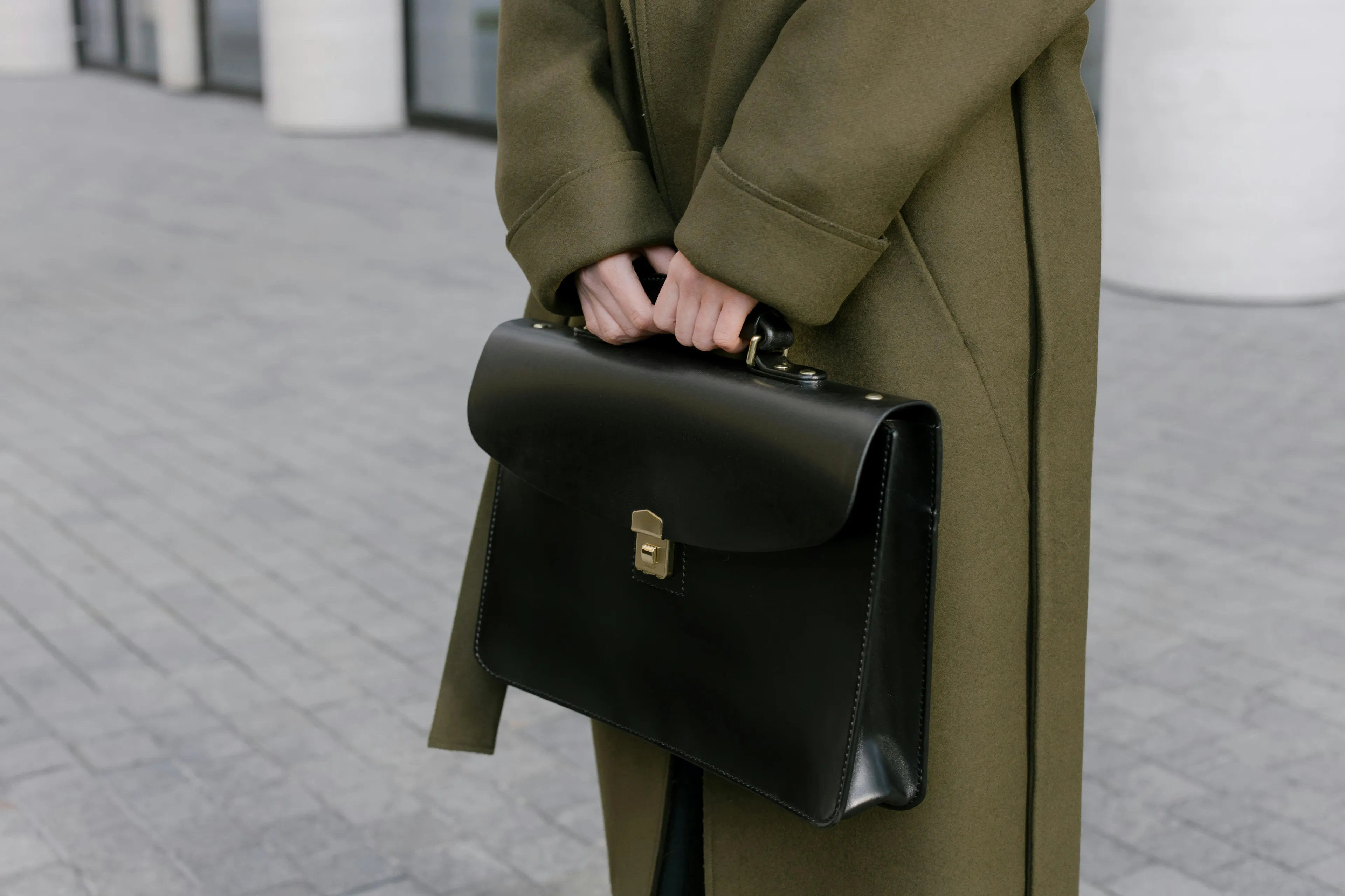 Person holding a black leather briefcase outdoors, highlighting differences general knowledge quiz on briefcases.