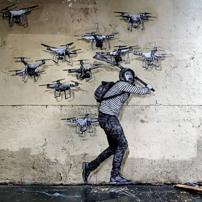 Hombre en mural de arte urbano intenta golpear drones voladores en pared urbana con estilo artístico impresionante.