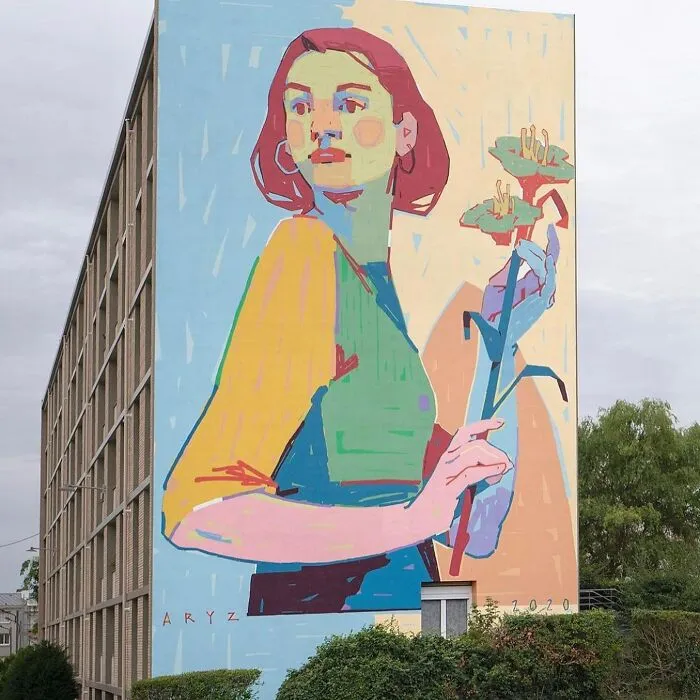 Mural de arte urbano colorido en edificio mostrando figura femenina con flores, obra impresionante de arte urbano contemporáneo.