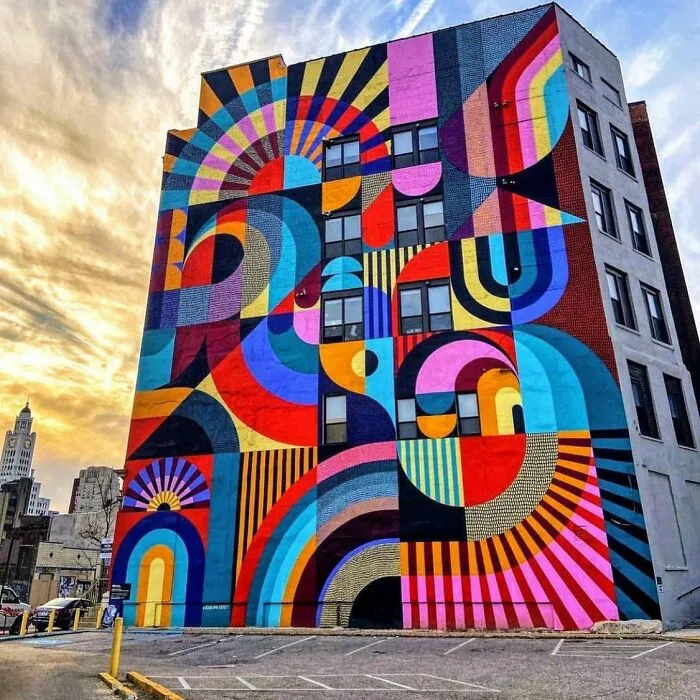 Mural de arte urbano colorido y geométrico en edificio, representando obra de arte urbano impresionante en la ciudad.