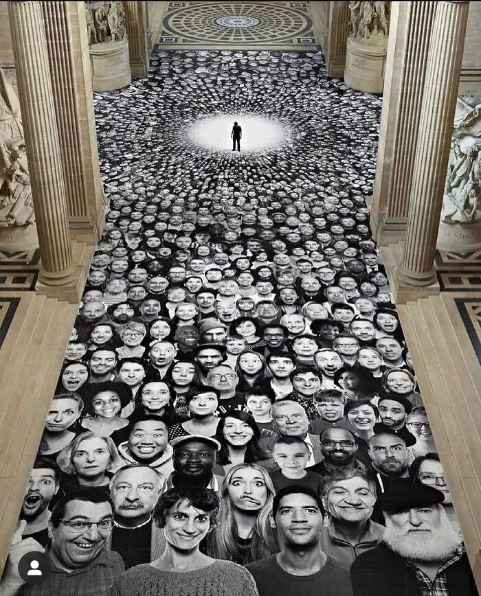 Obra de arte urbano impresionante que muestra cientos de rostros en blanco y negro creando una formación en círculo.
