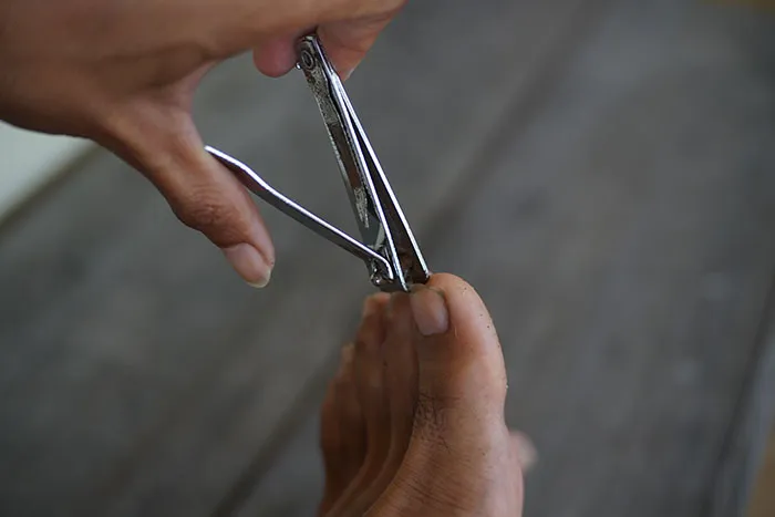 Person using nail clippers to trim toenails, illustrating coworkers who became legends for all the wrong reasons.