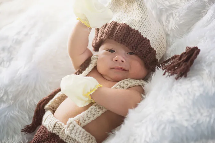 Baby lying on a soft blanket wearing knitted hat and mittens, symbolizing innocence unlike coworkers who became legends
