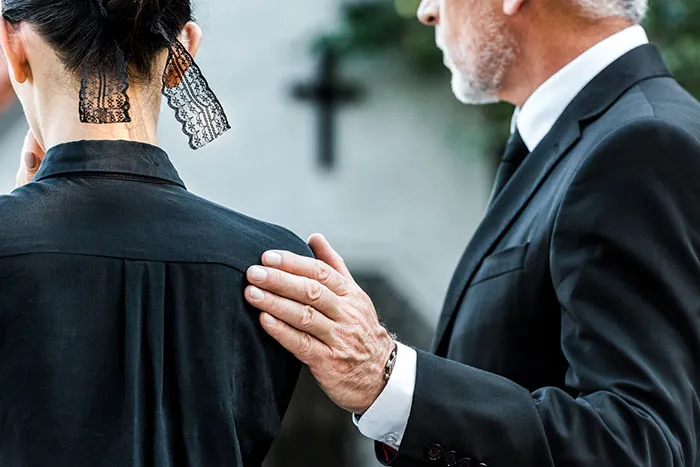 Man in suit placing hand on woman’s shoulder, representing coworkers who became legends for all the wrong reasons.
