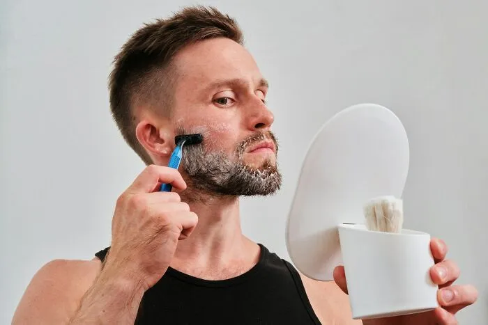 Man shaving with foam and razor, demonstrating a common grooming routine, related to well-known facts that are actually fake.