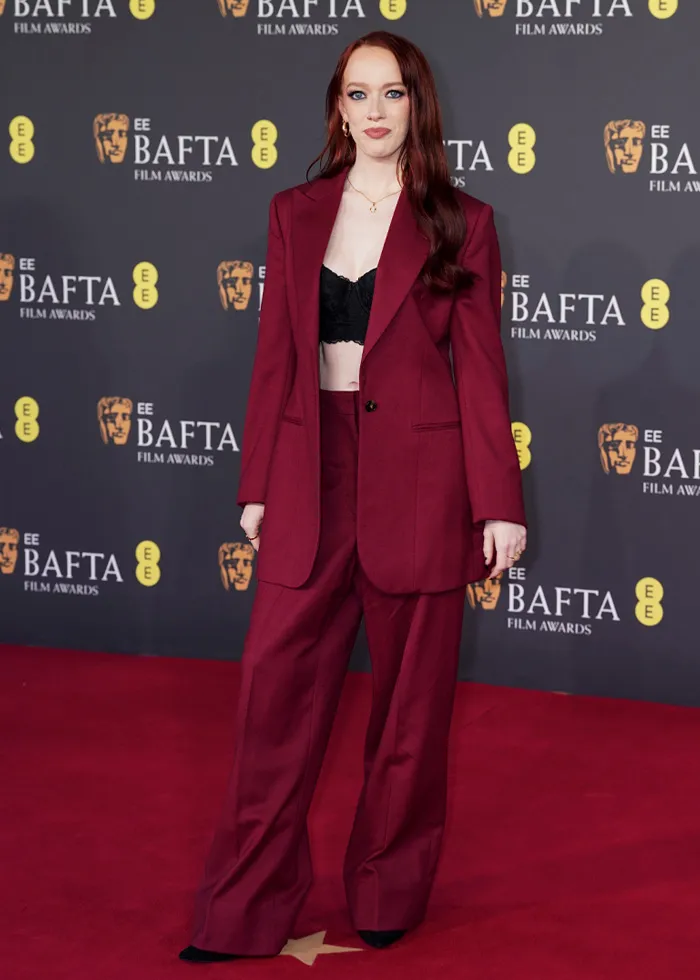 Woman in a black crop top and burgundy suit posing on the red carpet at the most talked-about BAFTA 2026 outfits event