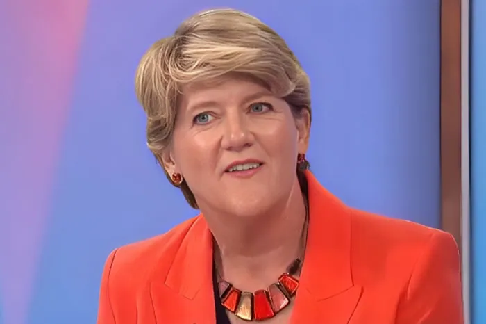 Woman in an orange blazer and colorful necklace speaking during a studio interview about Beyoncé fan reactions.