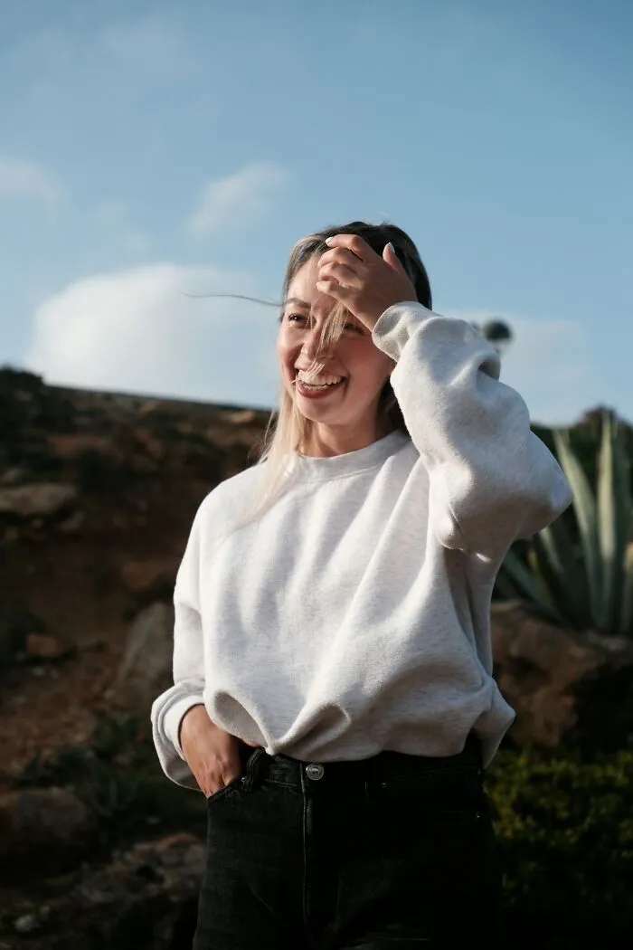 Young woman smiling outdoors in casual wear, reflecting on friendships ended without even starting in a natural setting.