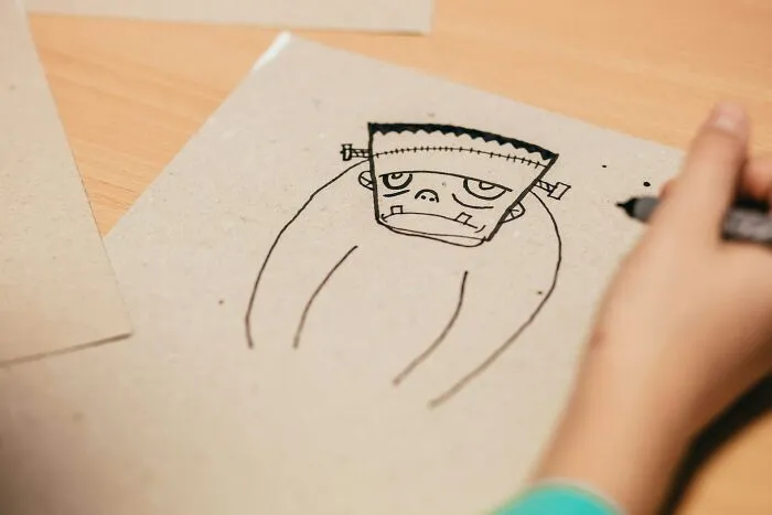 Child drawing a cartoonish Frankenstein character on paper, illustrating well-known facts that are actually fake.
