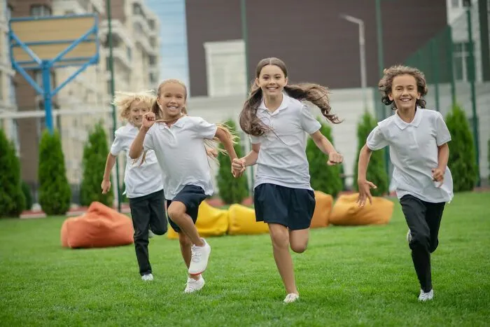Four children in white shirts running and laughing outdoors, illustrating well-known facts that are actually fake.