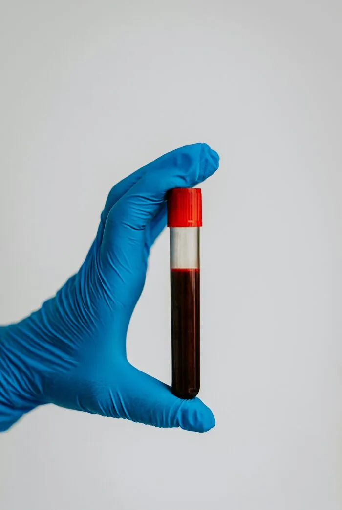 Hand in blue glove holding blood sample tube representing well-known facts that are actually fake in medical testing.
