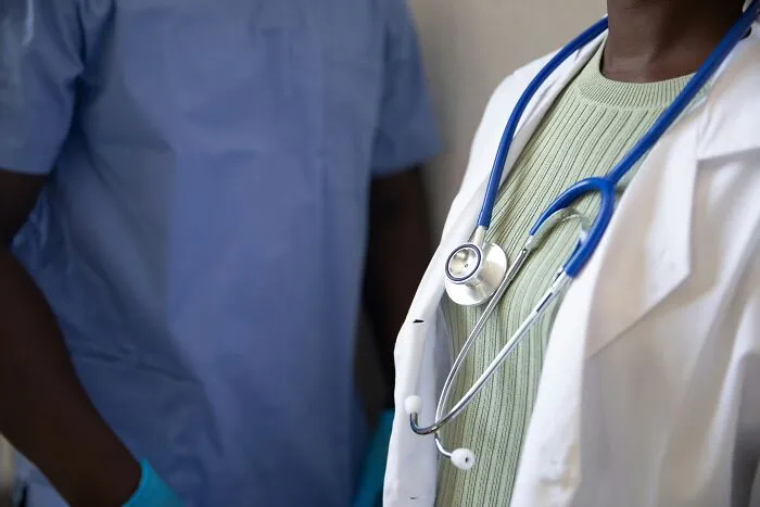Médicos con estetoscopios y uniformes atendiendo pacientes antivacunas en consulta médica.