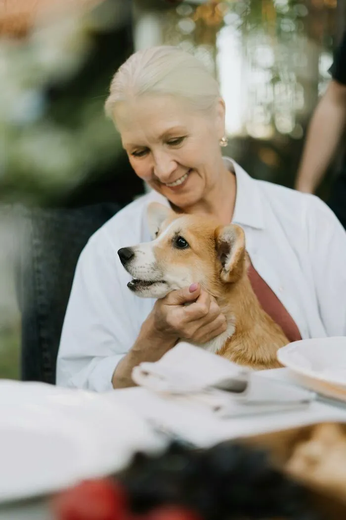Older woman smiling and holding a dog closely, illustrating how people silently judge others through actions.