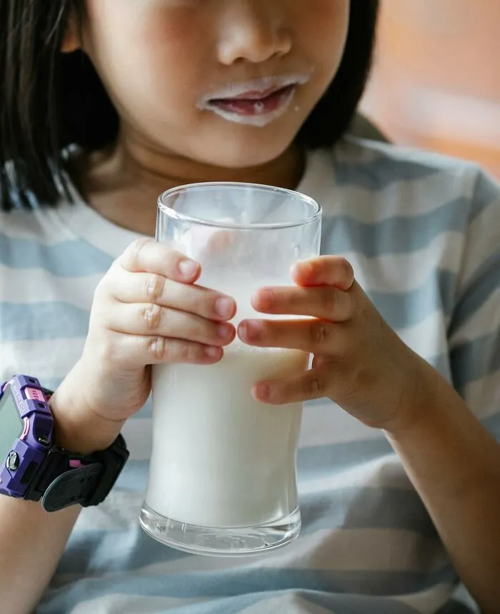 Child holding a glass of milk with a milk mustache, symbolizing saved a child's life and child protection awareness.