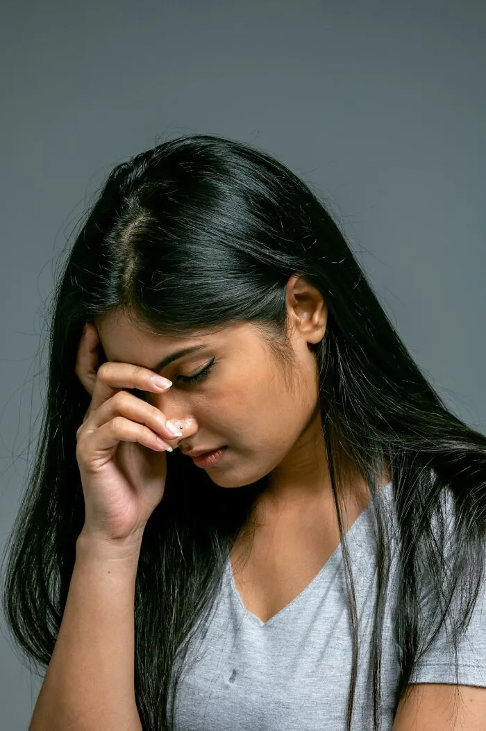 Woman with long black hair, looking distressed and contemplative, symbolizing reporting to CPS or police to save a child’s life.