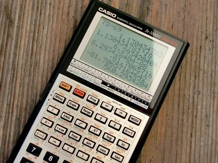 Scientific calculator displaying complex calculations on a wooden surface, highlighting moments of confusion and pause.