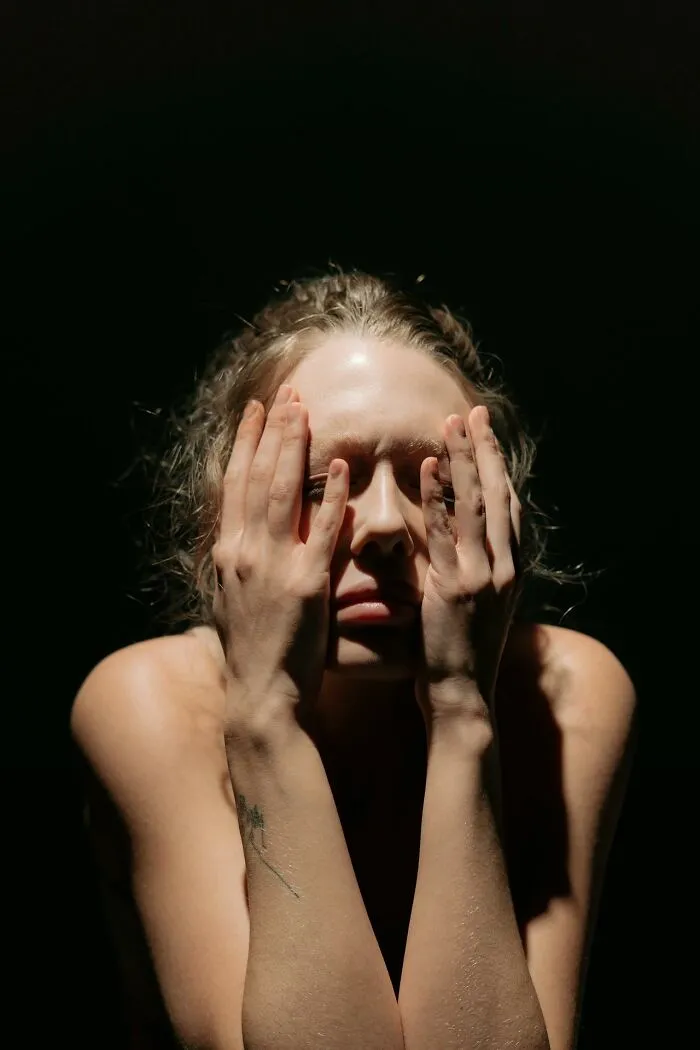 A distressed person covering their face with hands, symbolizing the emotional impact of reporting to CPS or police.