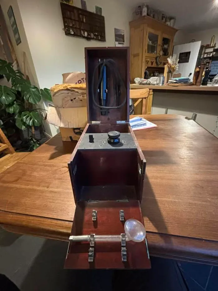 Antique wooden device with a glass bulb and metal parts displayed on a table, internet solved mystery of unidentified objects.