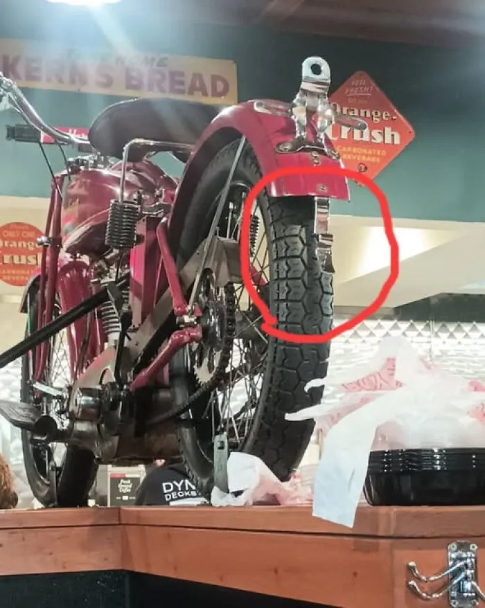 Vintage red motorized bicycle displayed indoors with a tire circled in red, illustrating unidentified objects solved online.
