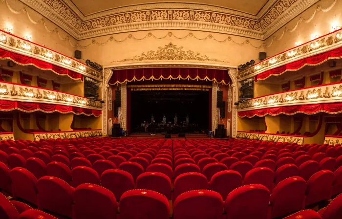 Ornate vintage theater with red velvet seats and balconies, setting a spine-chilling haunted place atmosphere.